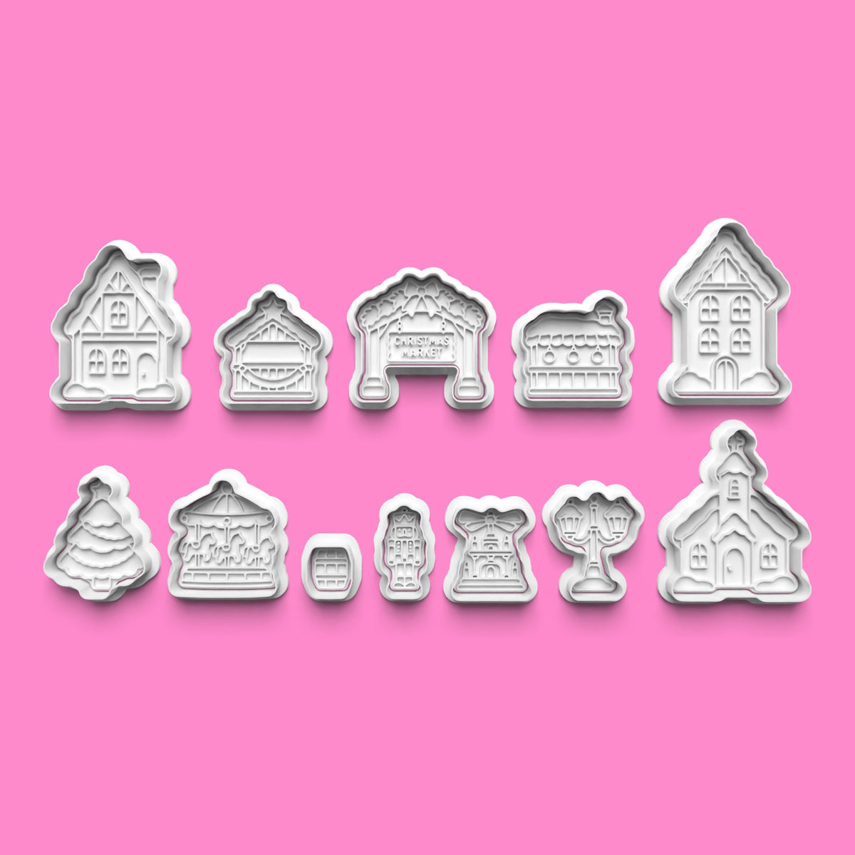 12-piece Christmas market village cookie cutter and embosser set featuring snow-covered houses, market stalls, Christmas tree, carousel, church and festive street decorations.