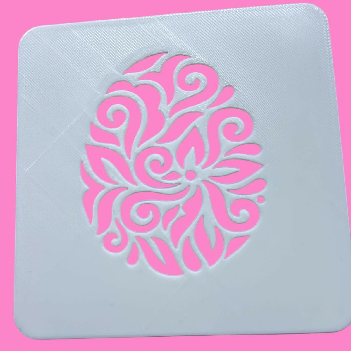 A white square food stencil with a pink floral egg pattern design.