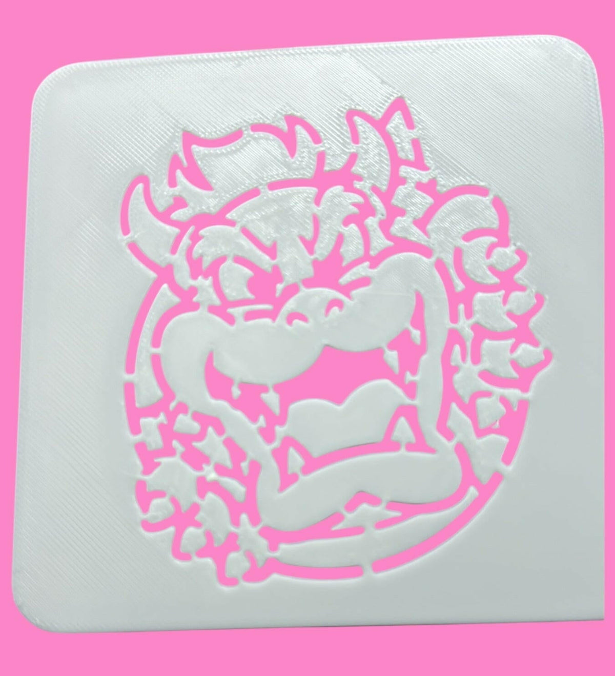 A white square food-safe PLA stencil with a pinkBowser-inspired design for cookie, cake, and fondant decorating.