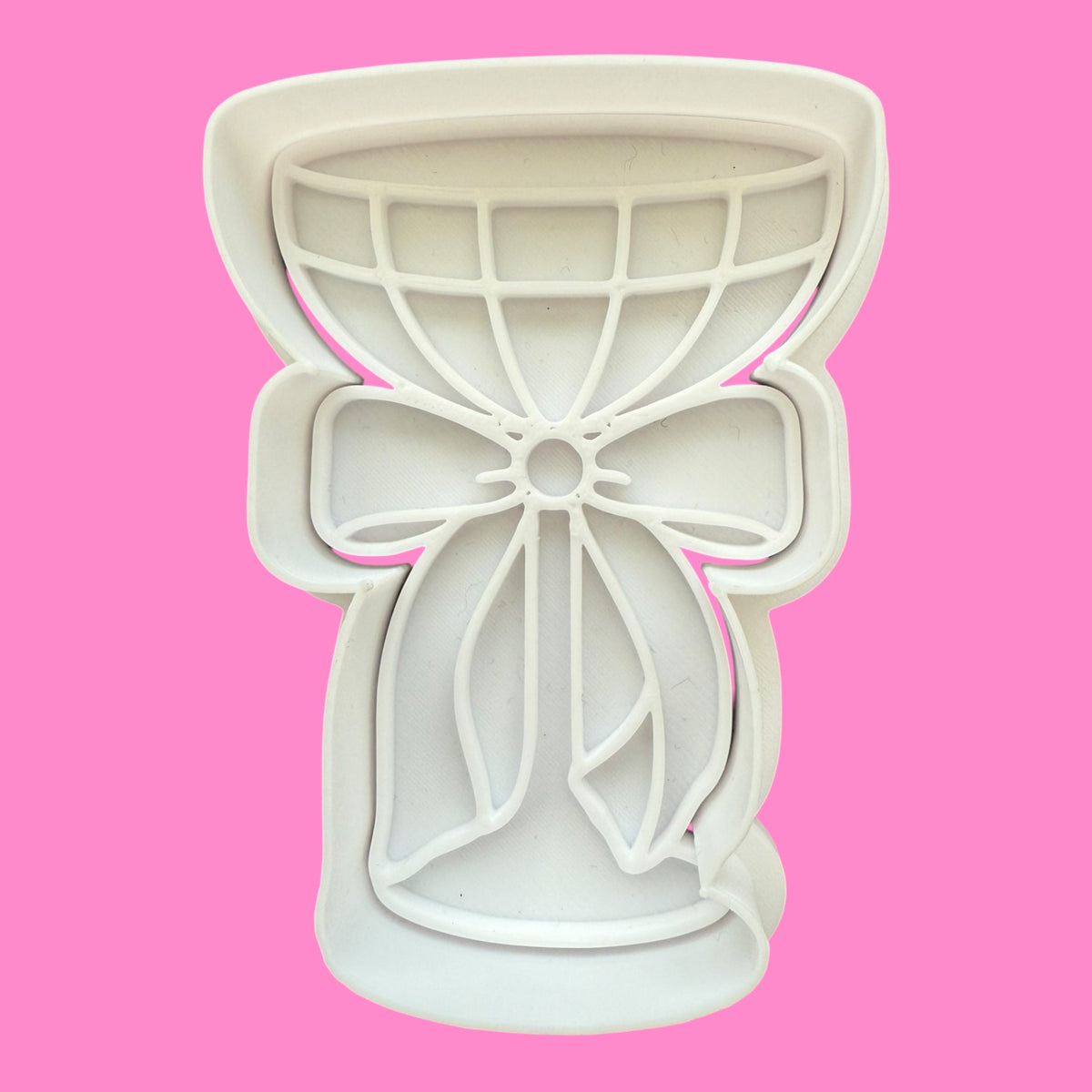 Bow-shaped cookie cutter on a pink background