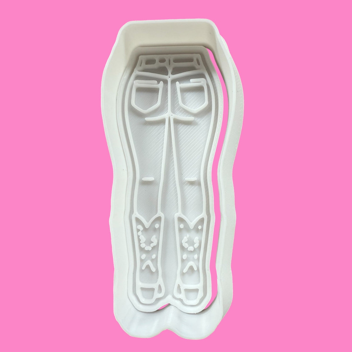 A plastic cookie cutter and embosser in the shape of a silhouette of a person wearing denim jeans and cowboy boots.