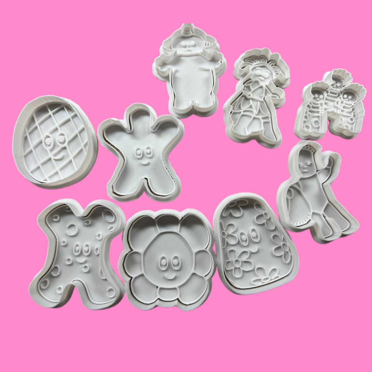 A collection of cookie cutters in various shapes including an iggle piggle character, a teddy bear, and other themed designs for baking.
