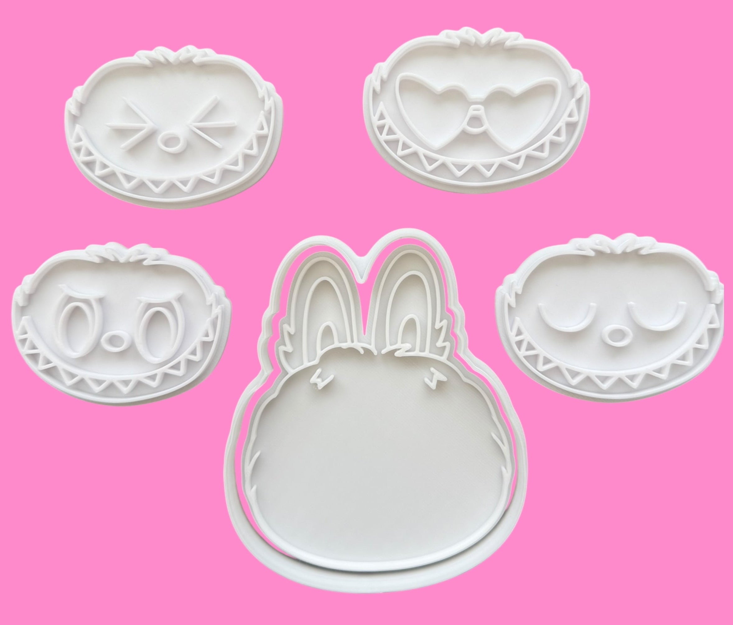 Set of cookie cutters with various shapes on a pink background