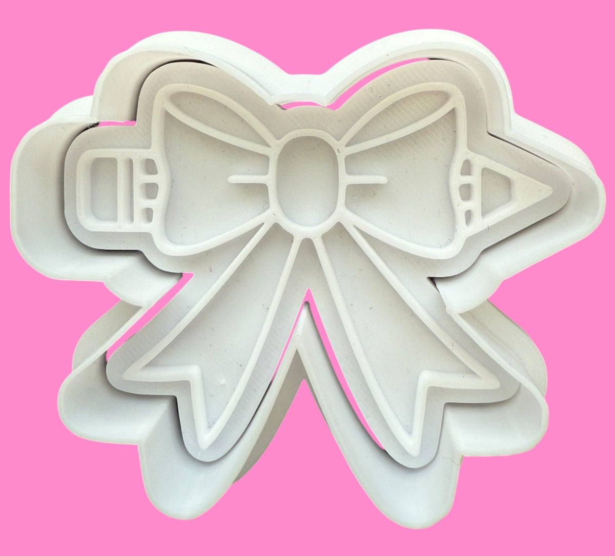 Bow-shaped cookie cutter on a pink background