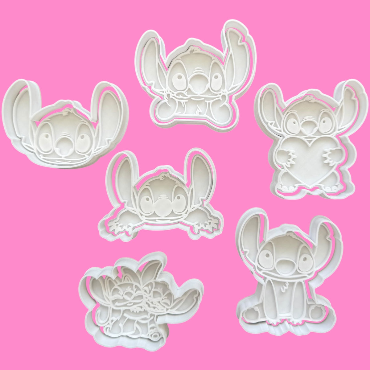 Set of six white cartoon character cookie cutters on a pink background