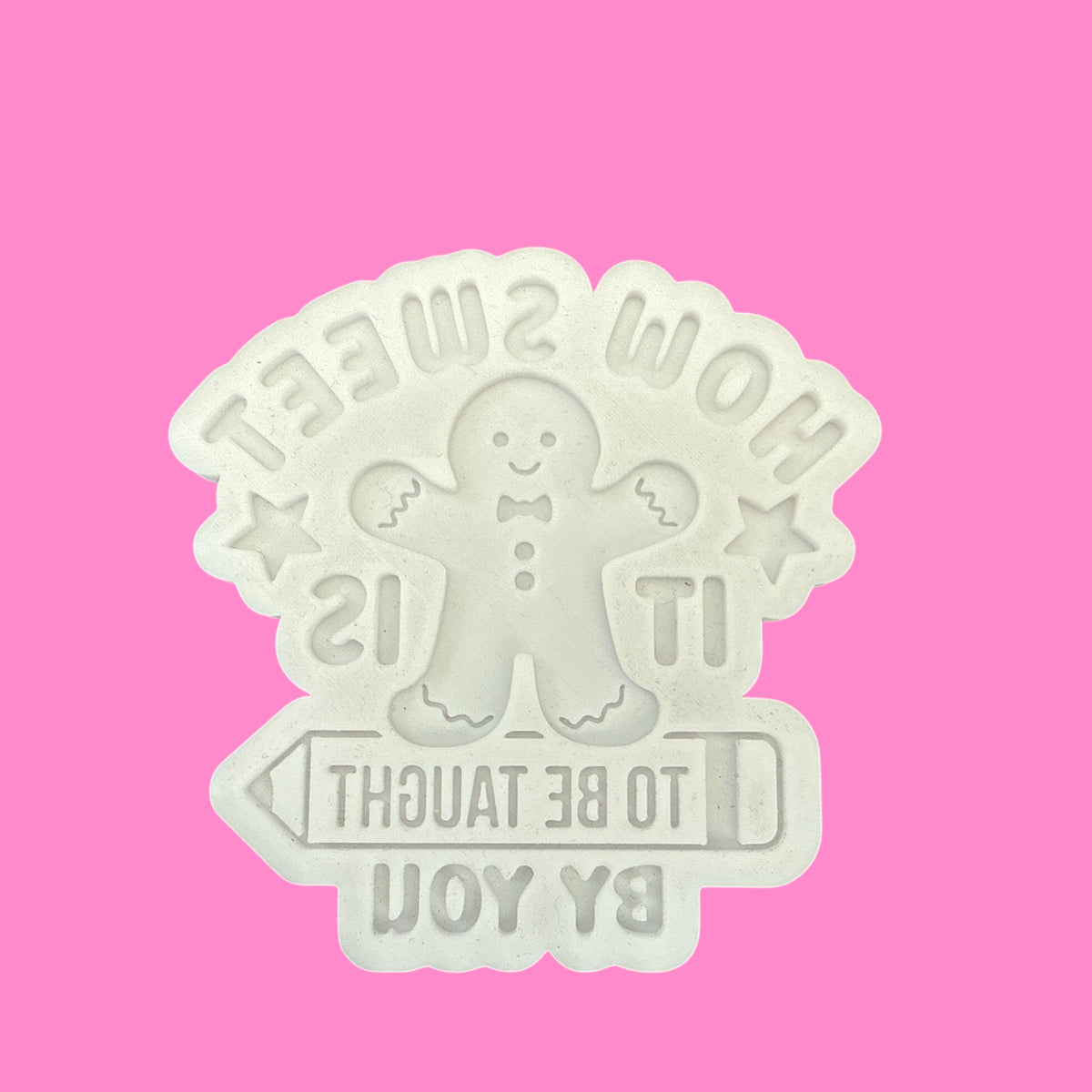 White cookie cutter with a gingerbread man design on a pink background
