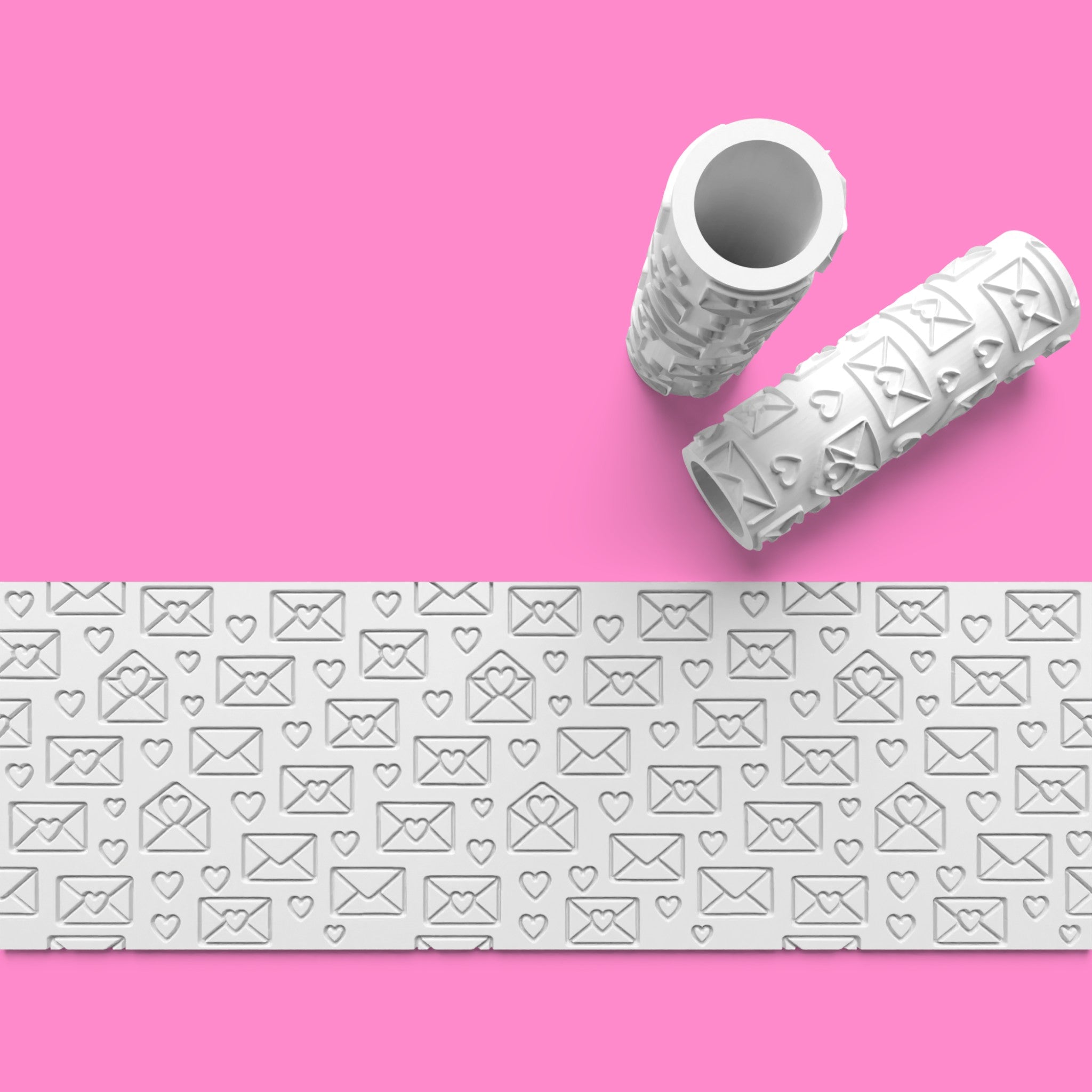 Two embossing folders with letter and heart patterns on a pink background