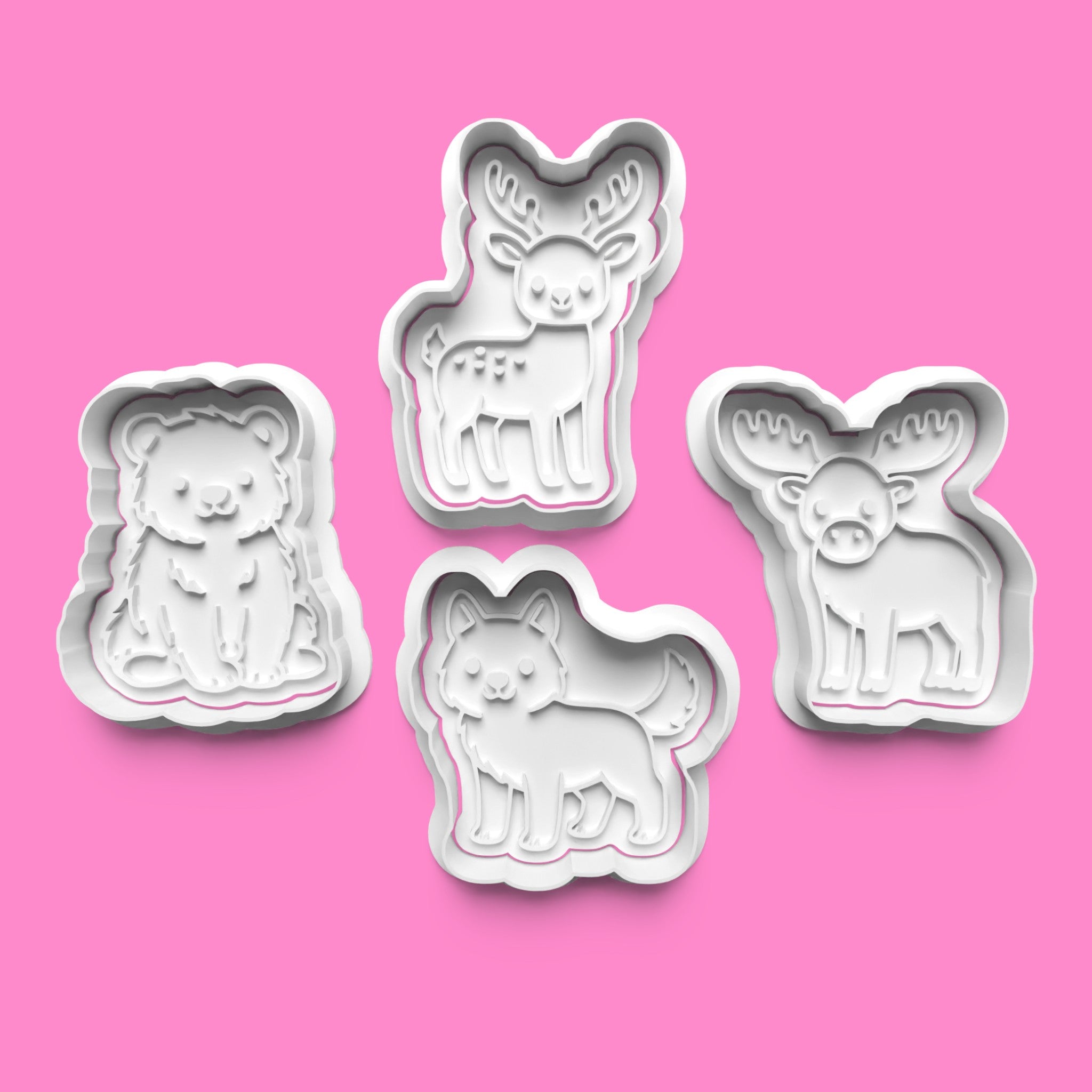 Set of four animal-shaped cookie cutters on a pink background