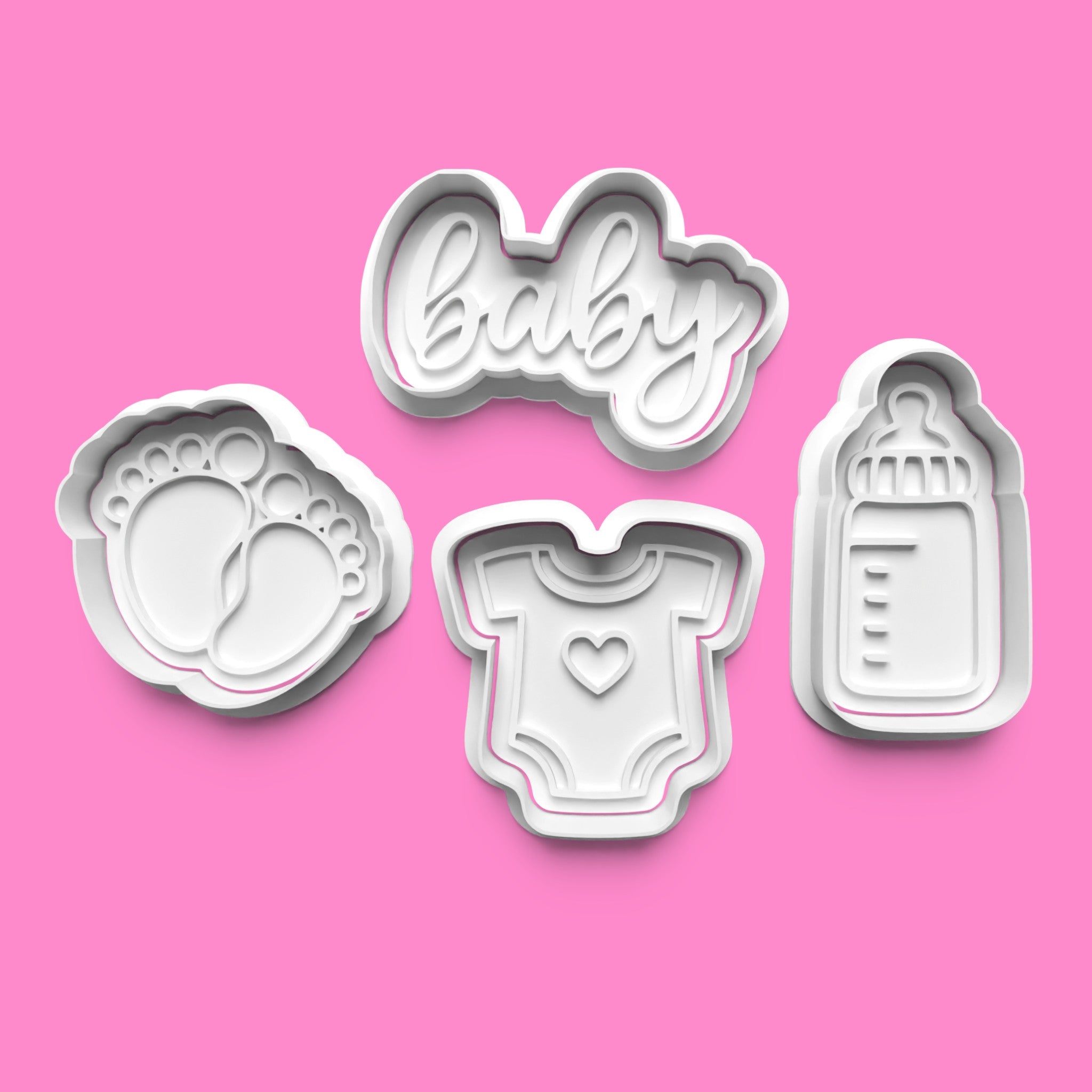 Set of cookie cutters shaped like baby items on a pink background