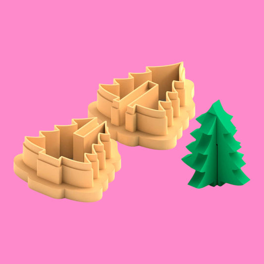 Two beige cookie cutters shaped like Christmas trees on a pink background with a green paper tree.
