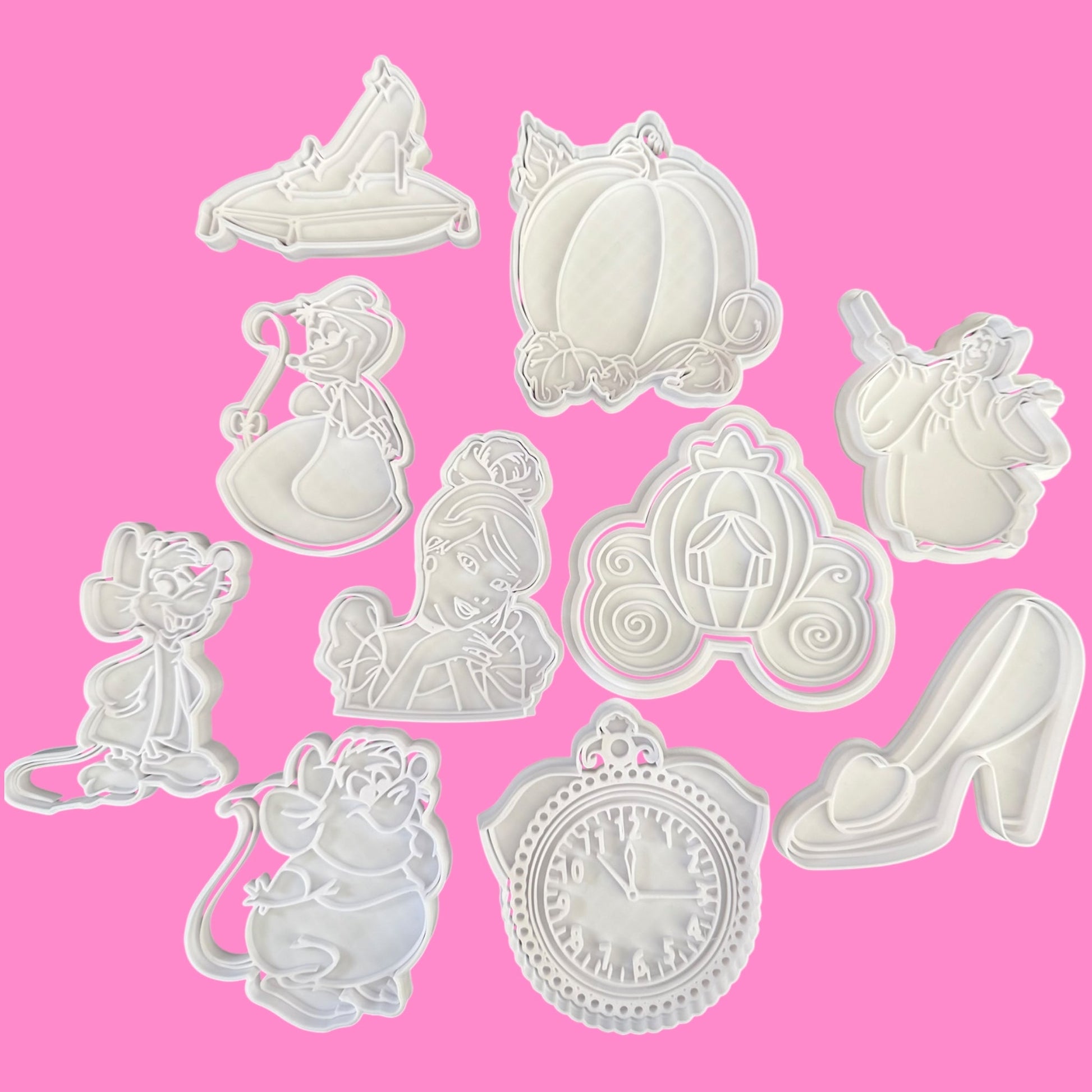 Set of white cookie cutters shaped like characters and objects on a pink background