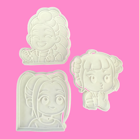 Three cookie cutters with cartoon character designs on a pink background