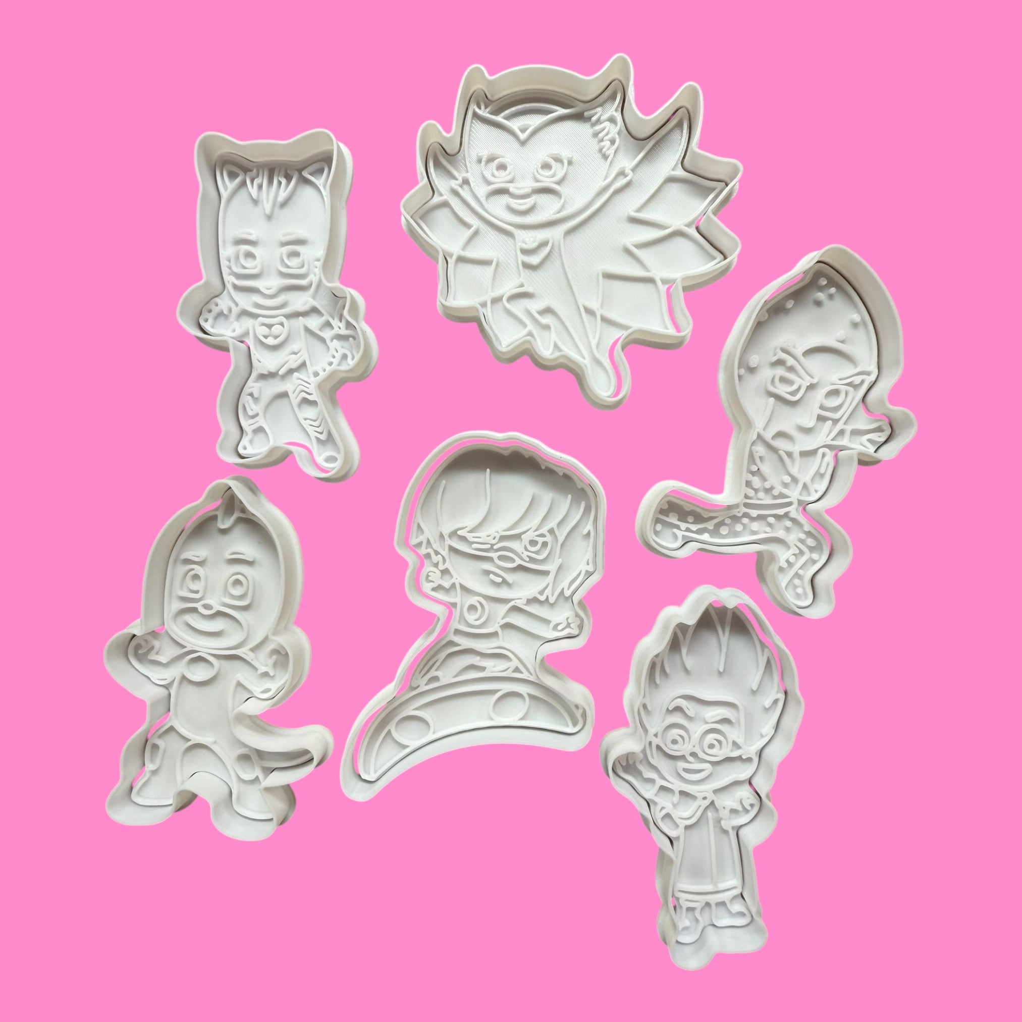 Set  PJ mask cookie cutters shaped like cartoon characters on a pink background