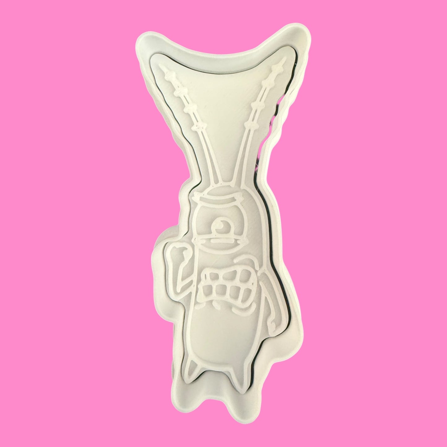 Metallic fish-shaped cookie cutter on a pink background