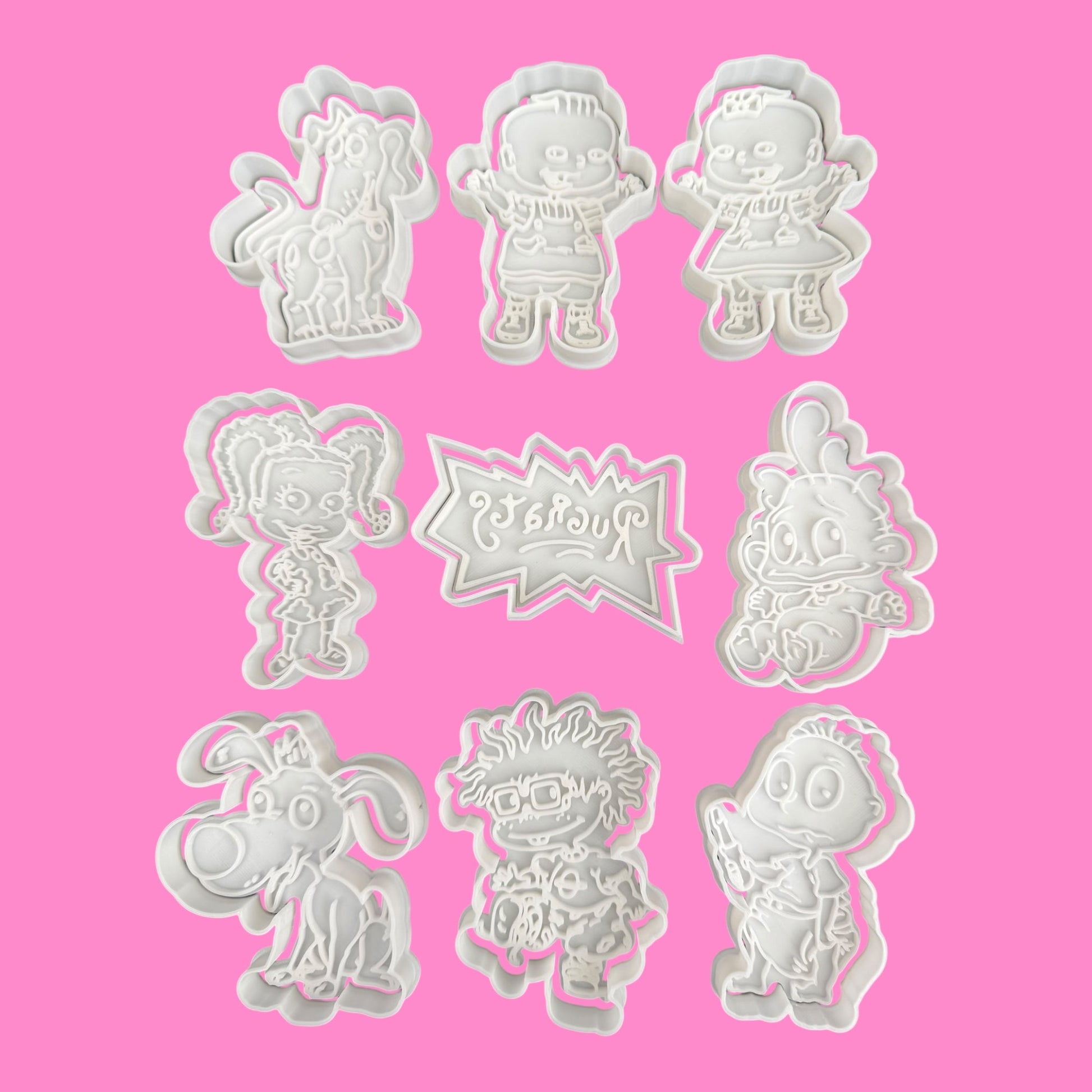 Set of cartoon character cookie cutters on a pink background