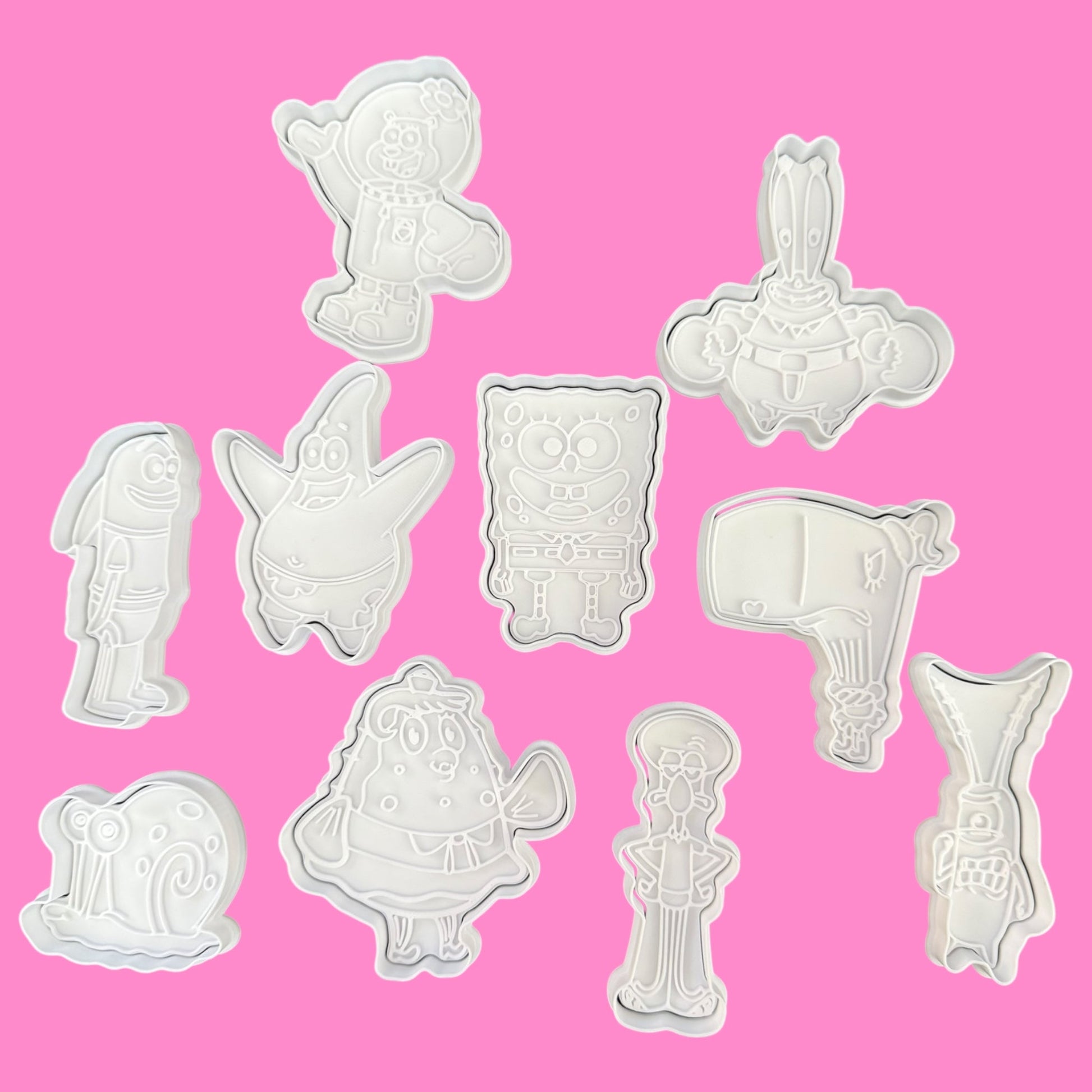 Set of various animal-shaped cookie cutters on a pink background