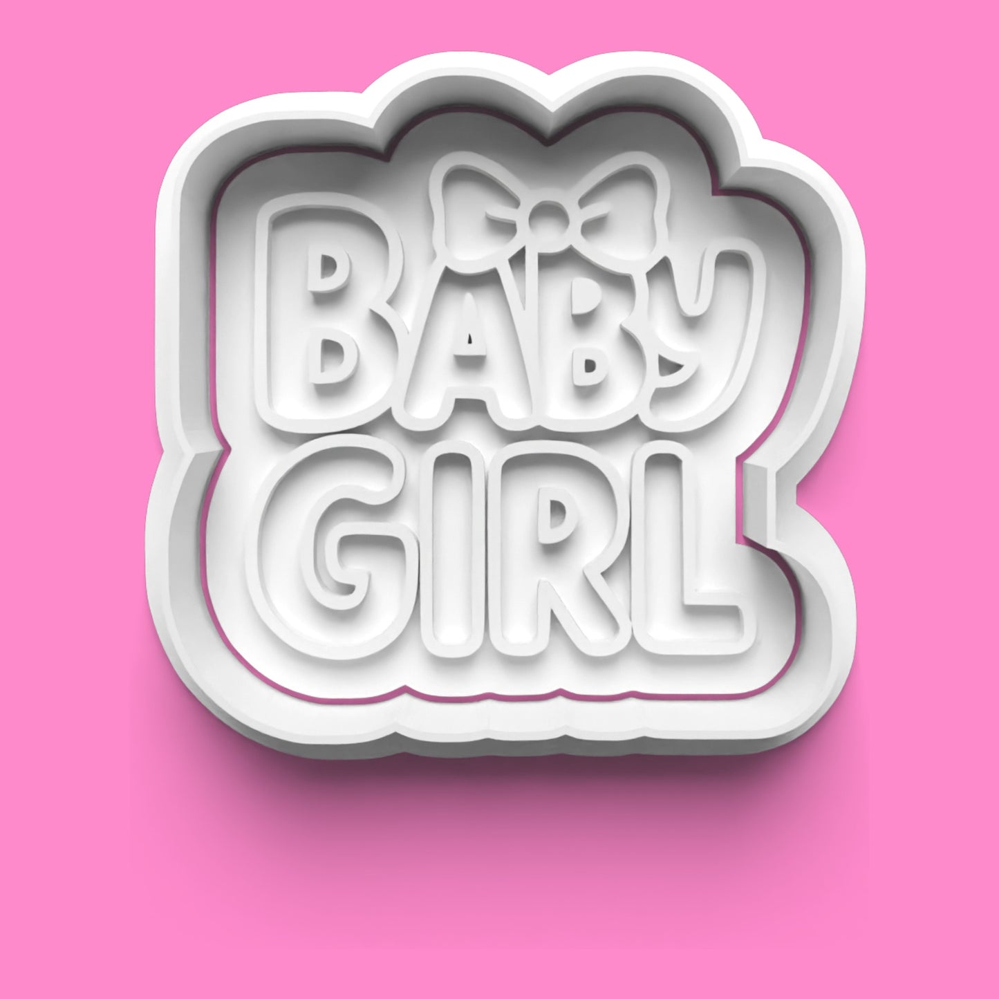 Cookie cutter with 'BABY GIRL' text and a bow on a pink background