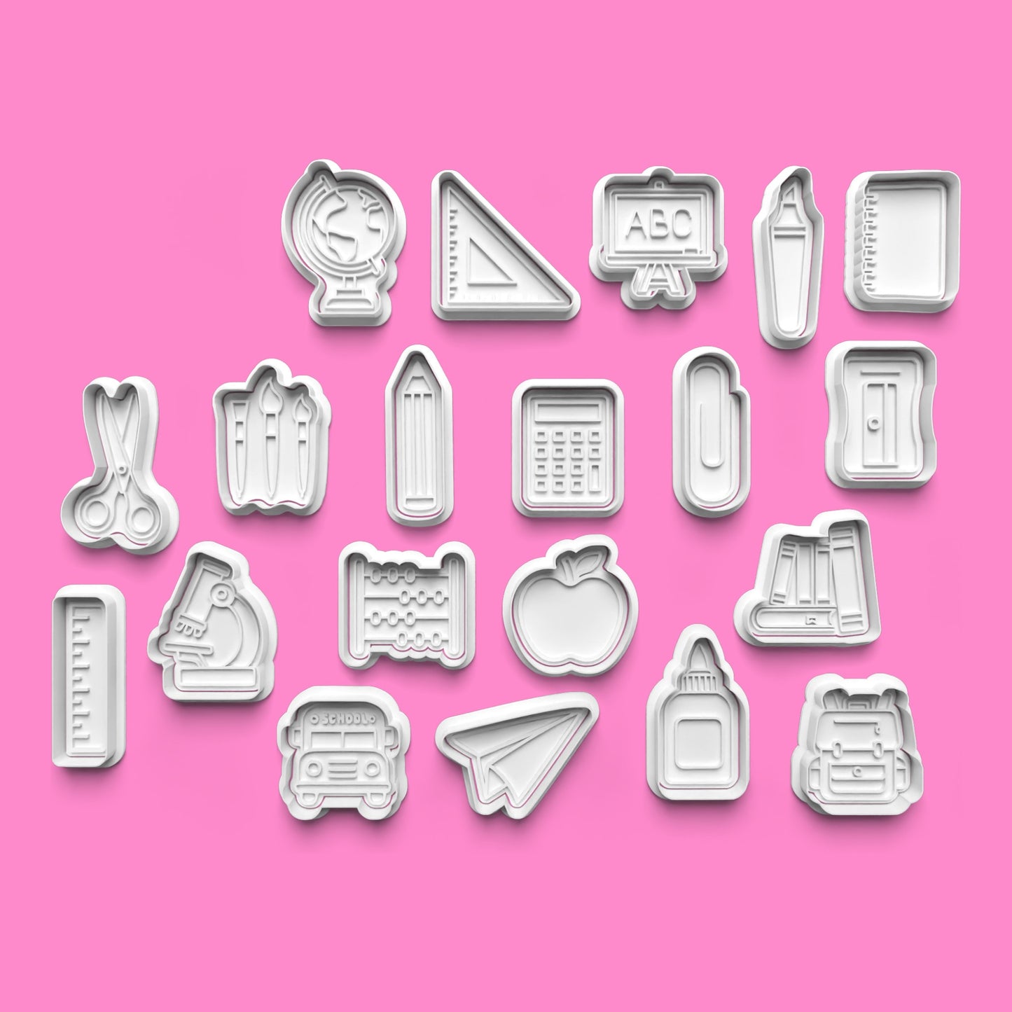 Set of cookie cutters with various shapes on a pink background