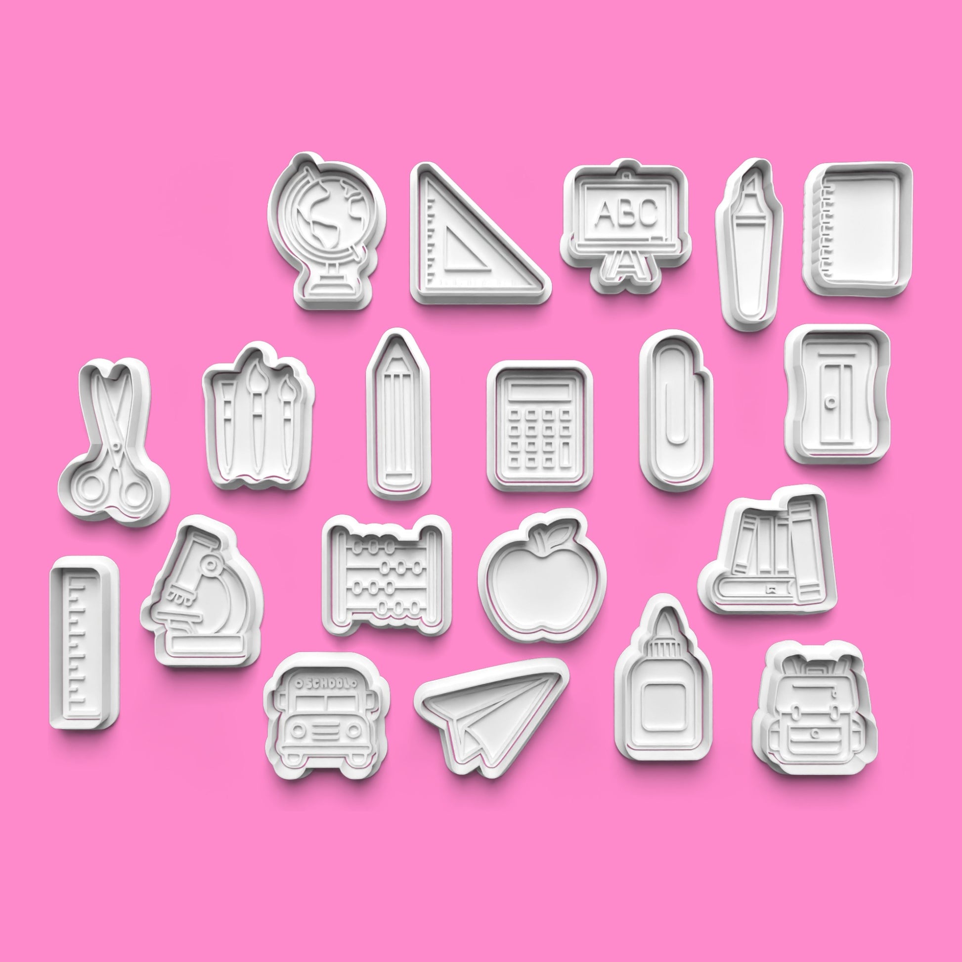 Set of cookie cutters with various shapes on a pink background