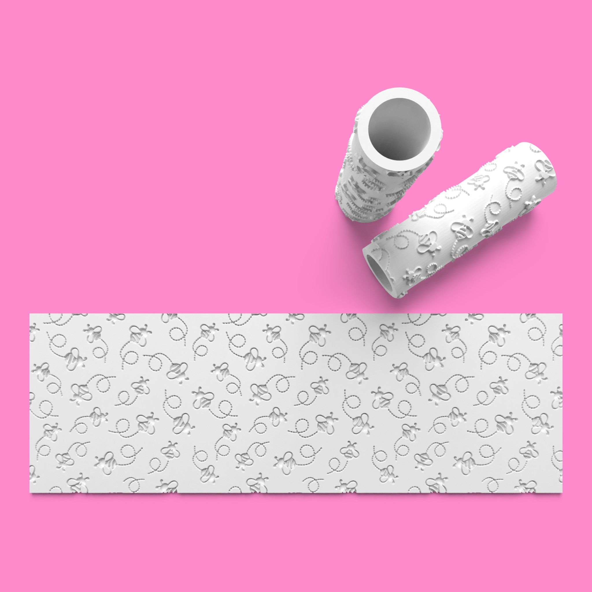 White textured roller and paper on a pink background