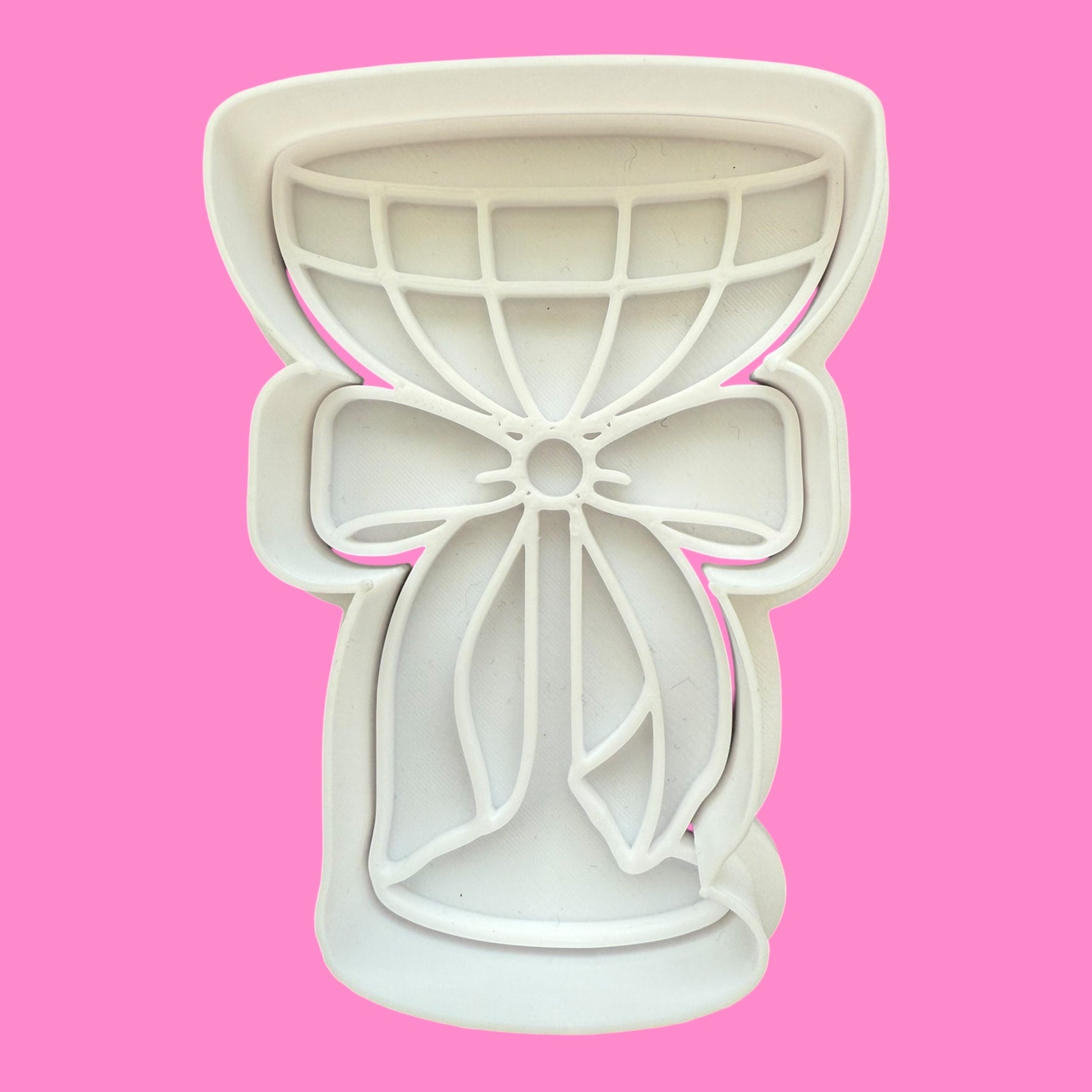Bow-shaped cookie cutter on a pink background