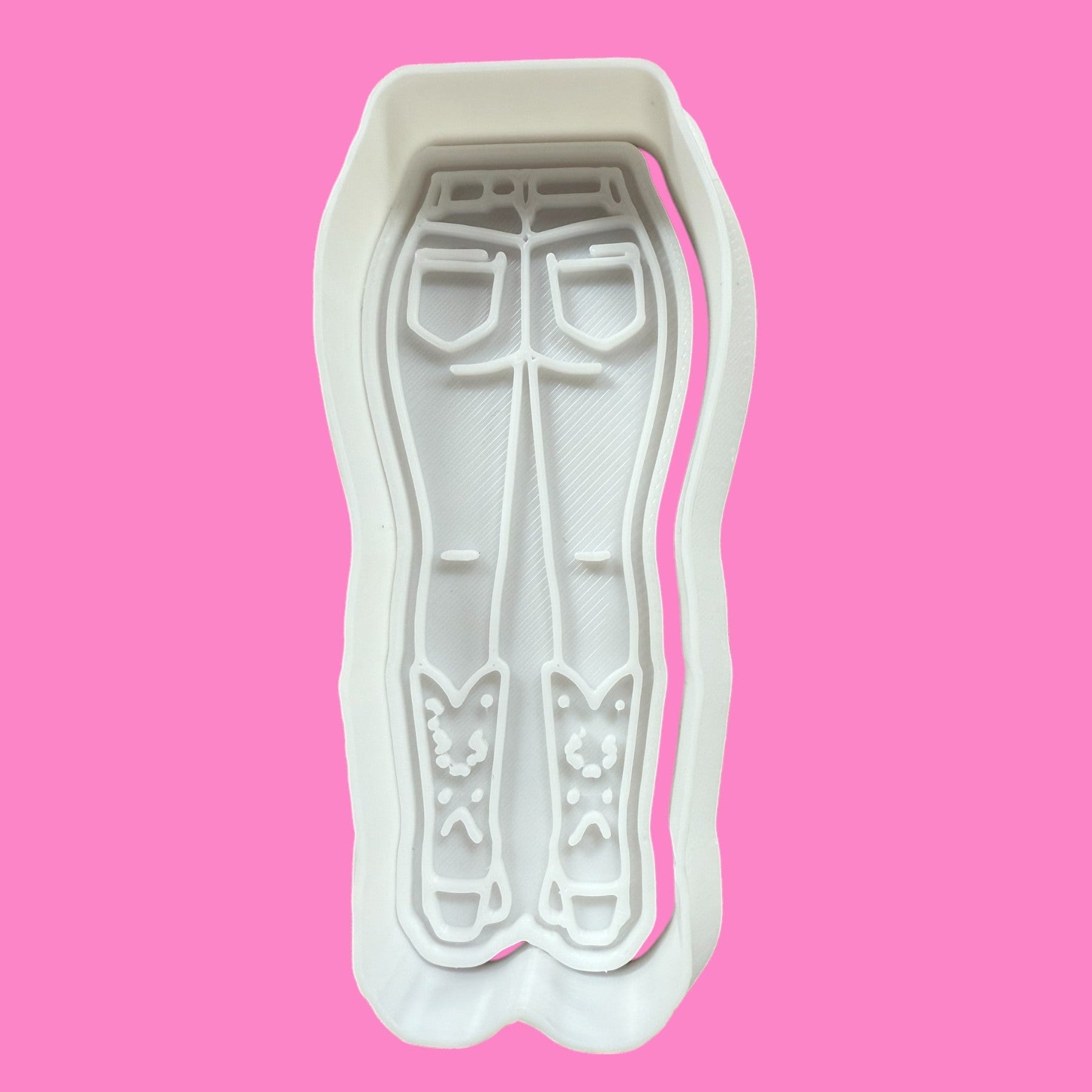 A plastic cookie cutter and embosser in the shape of a silhouette of a person wearing denim jeans and cowboy boots.