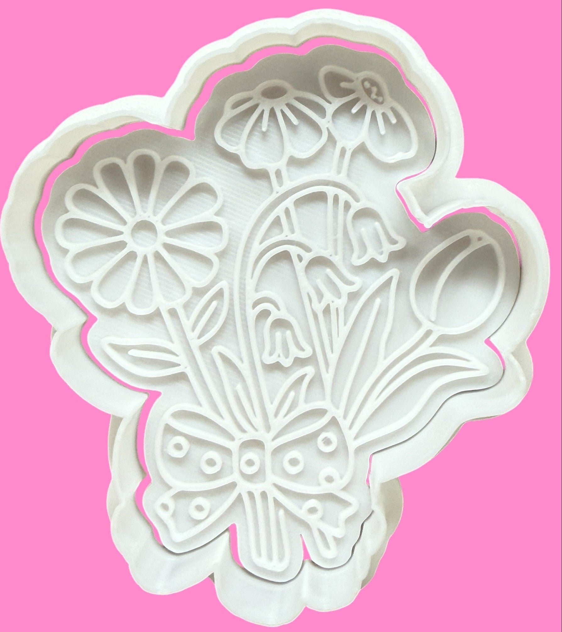 A white floral bouquet-shaped cookie cutter with detailed petals and a ribbon at the top.