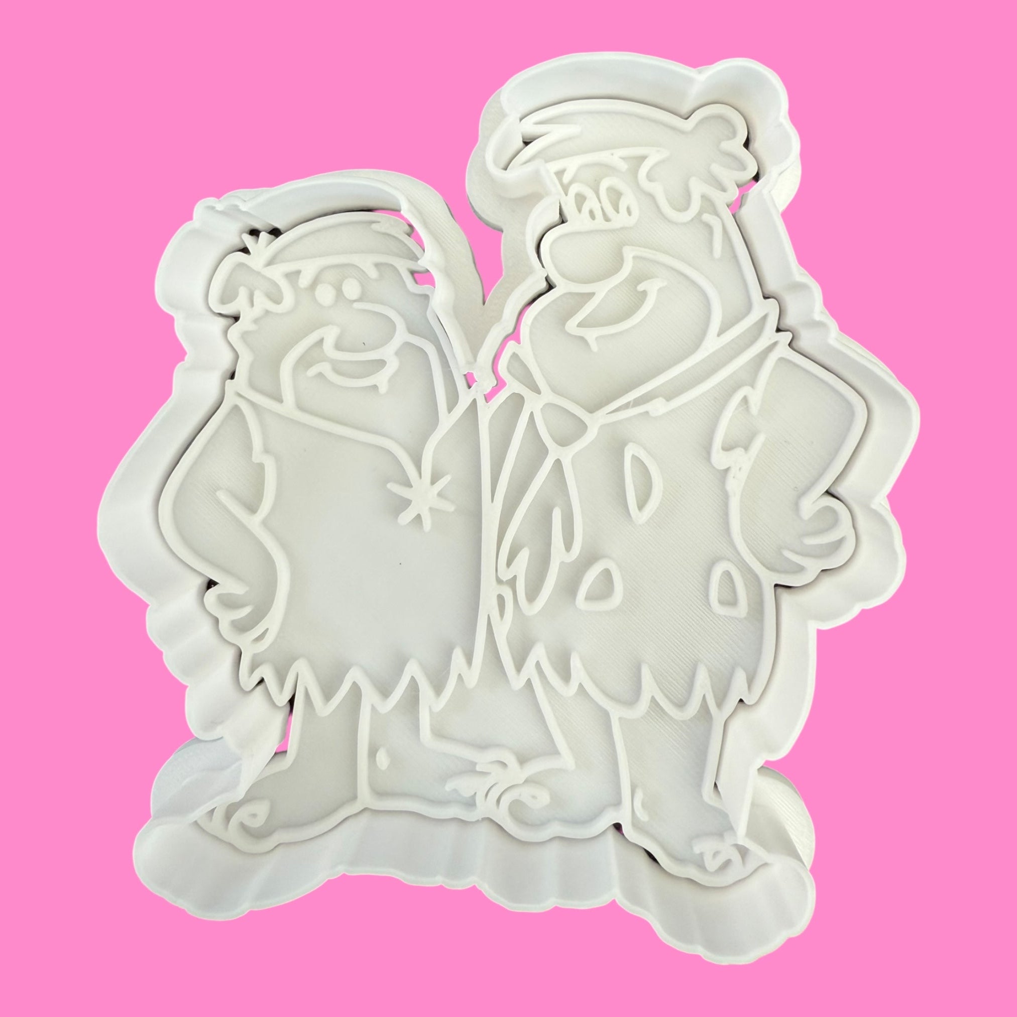 Two cookie cutters shaped like cartoon characters on a pink background