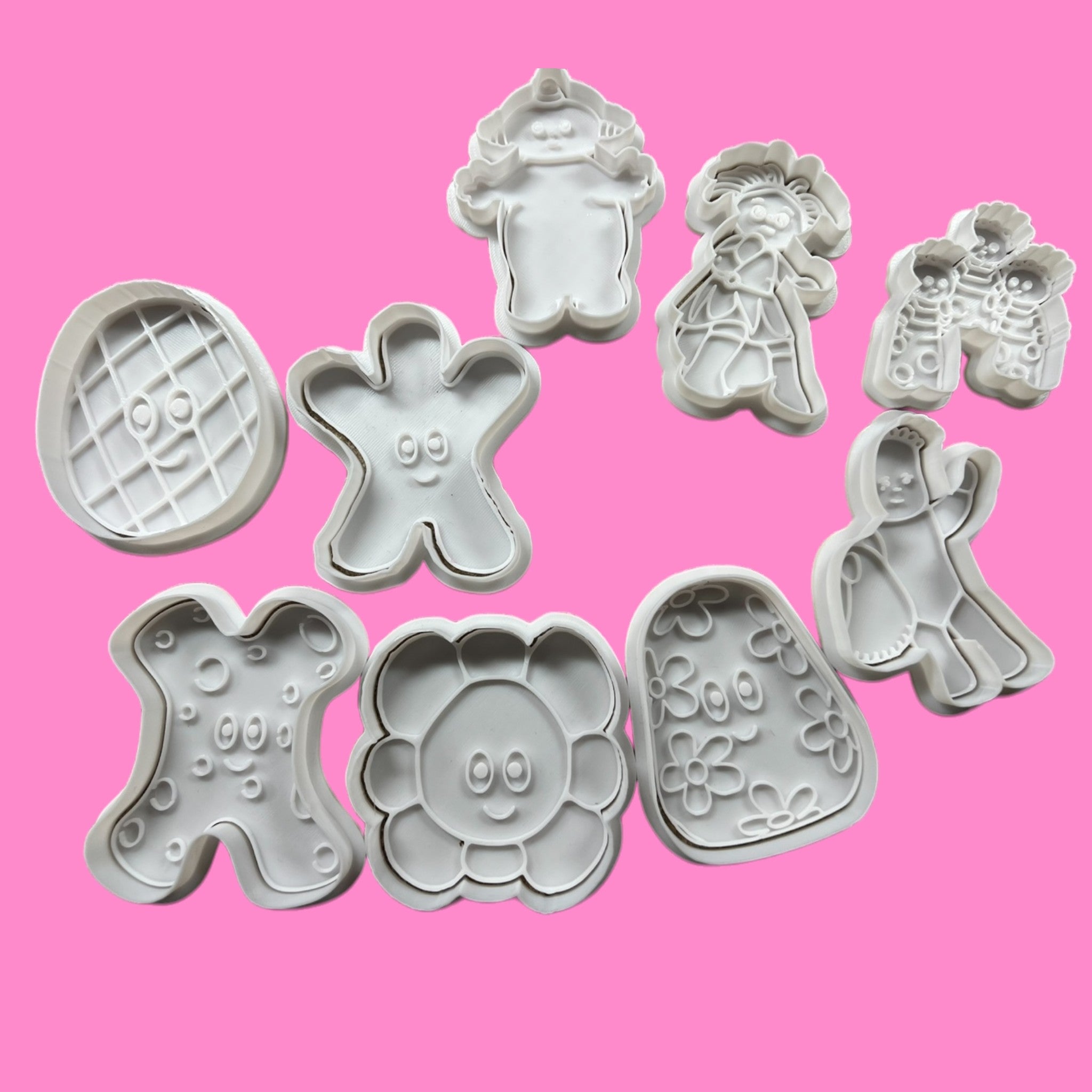 A collection of cookie cutters in various shapes including an iggle piggle character, a teddy bear, and other themed designs for baking.