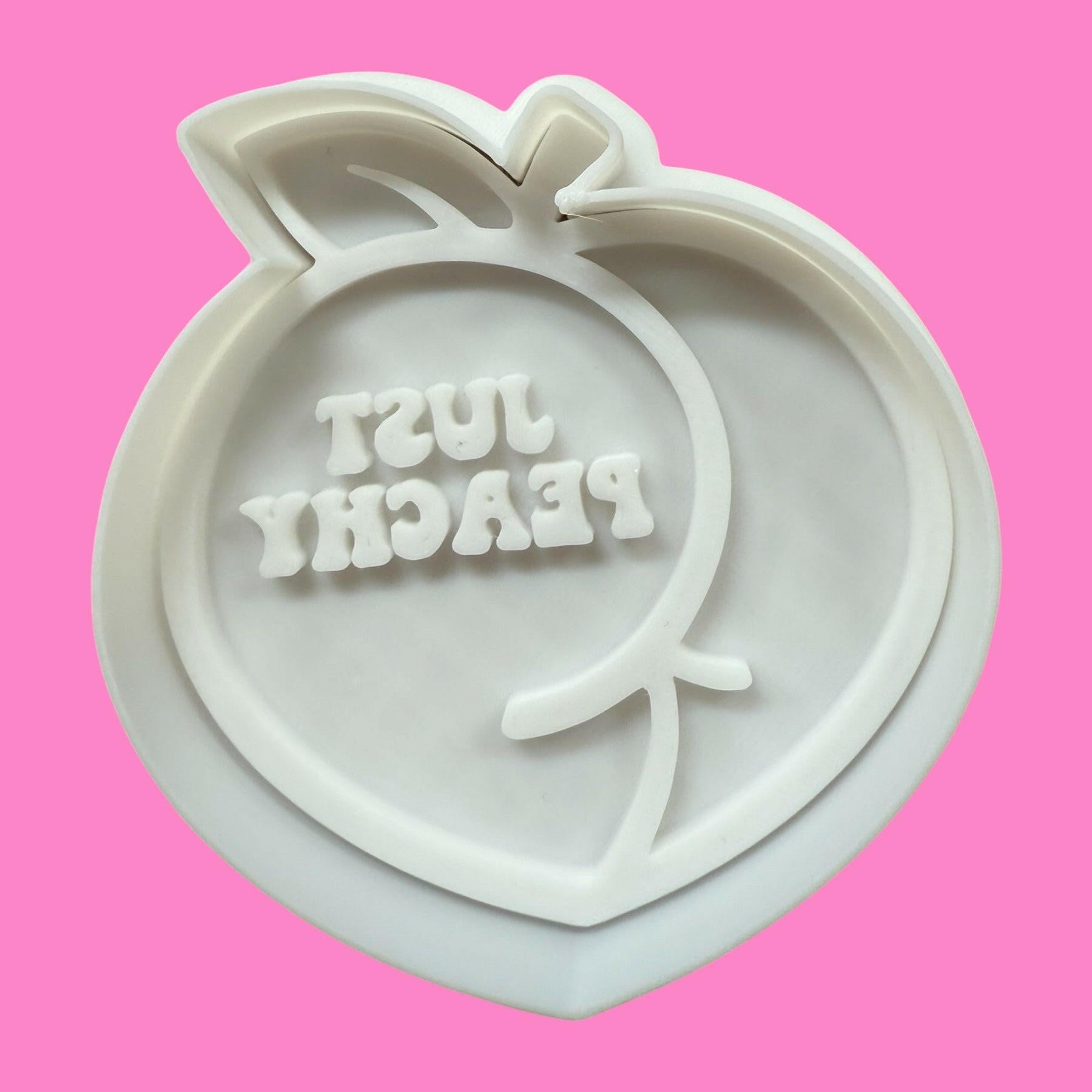 A cookie cutter and stamp set with a peach design and the text 'JUST PEACHY' inscribed on it.