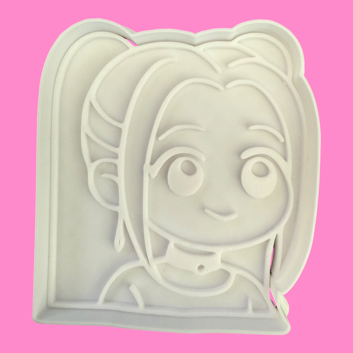 Cookie cutter with a cartoon character face on a pink background