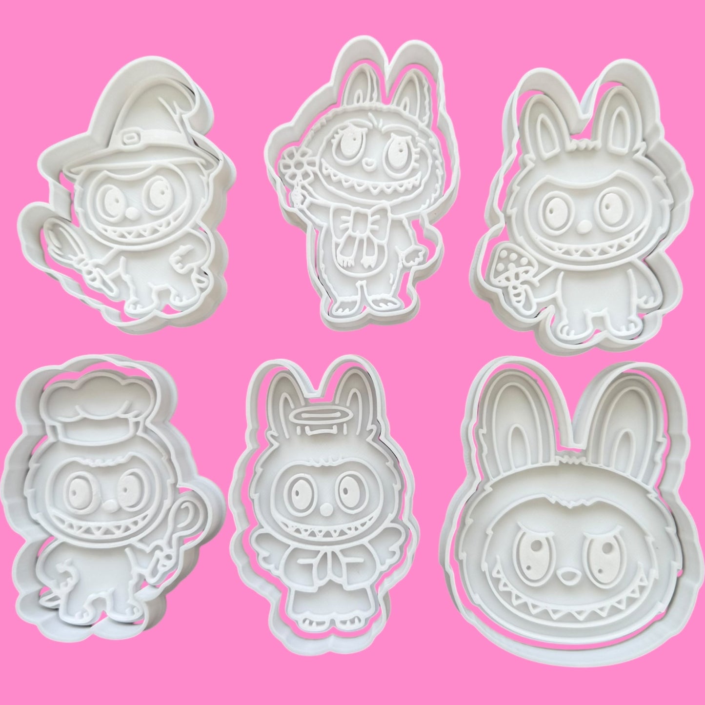 Set of six cartoon character cookie cutters on a pink background