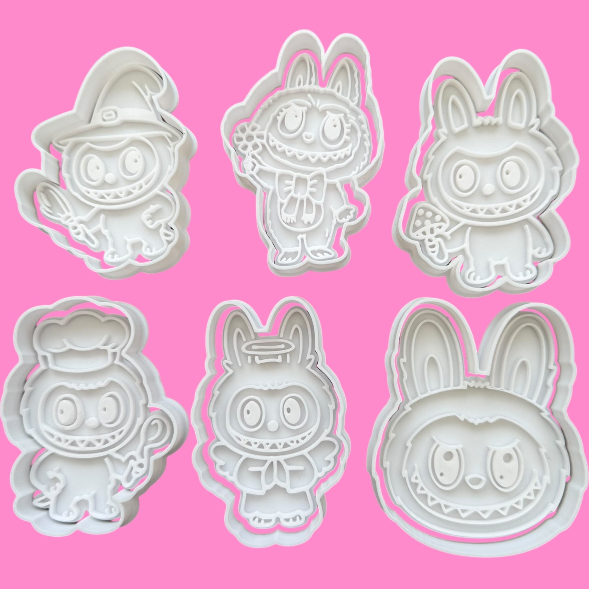 Set of six cartoon character cookie cutters on a pink background