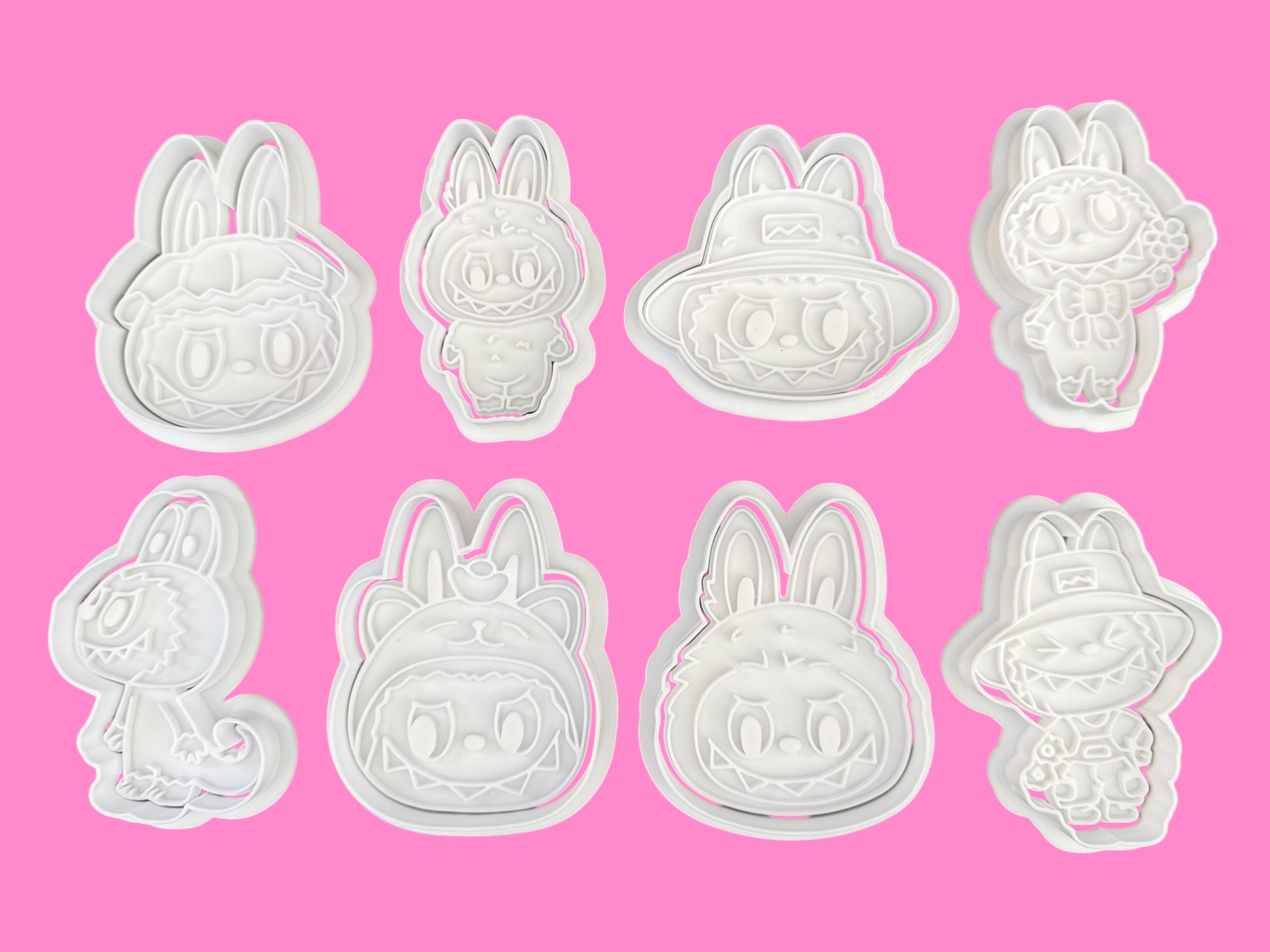 Set of eight white bunny-shaped cookie cutters on a pink background