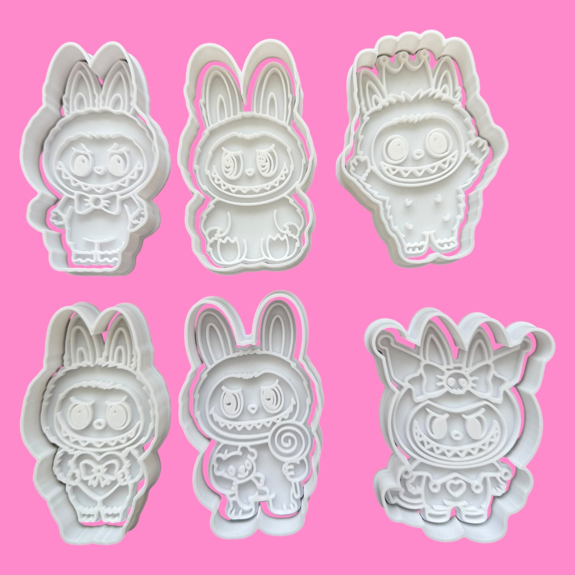 Set of six cartoon character cookie cutters on a pink background