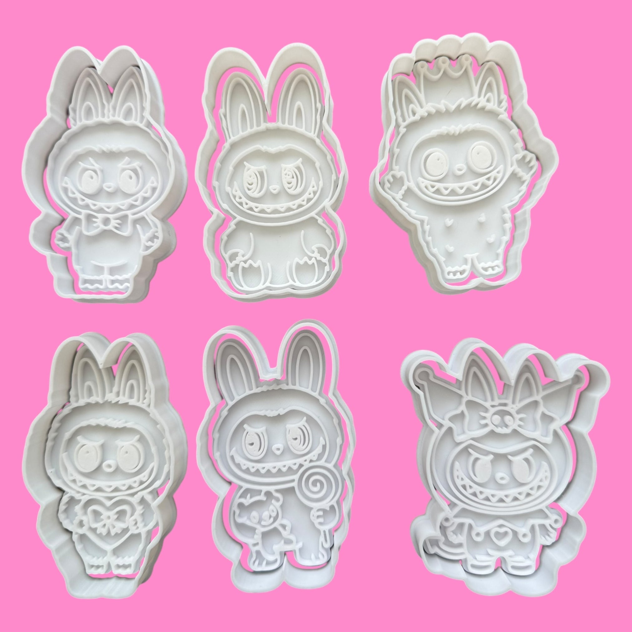 Set of six cartoon character cookie cutters on a pink background