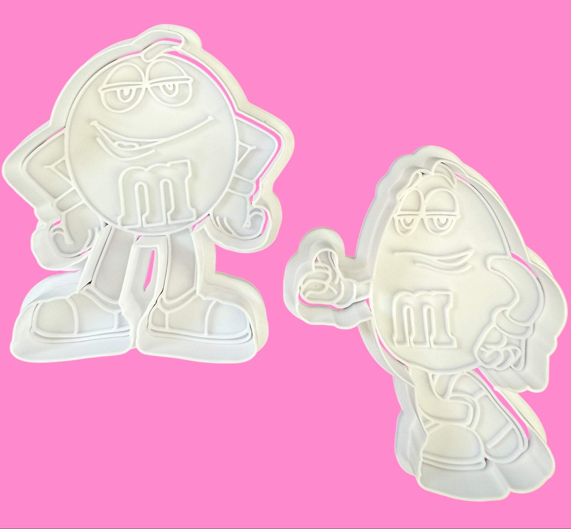 Two cartoon character cookie cutters on a pink background