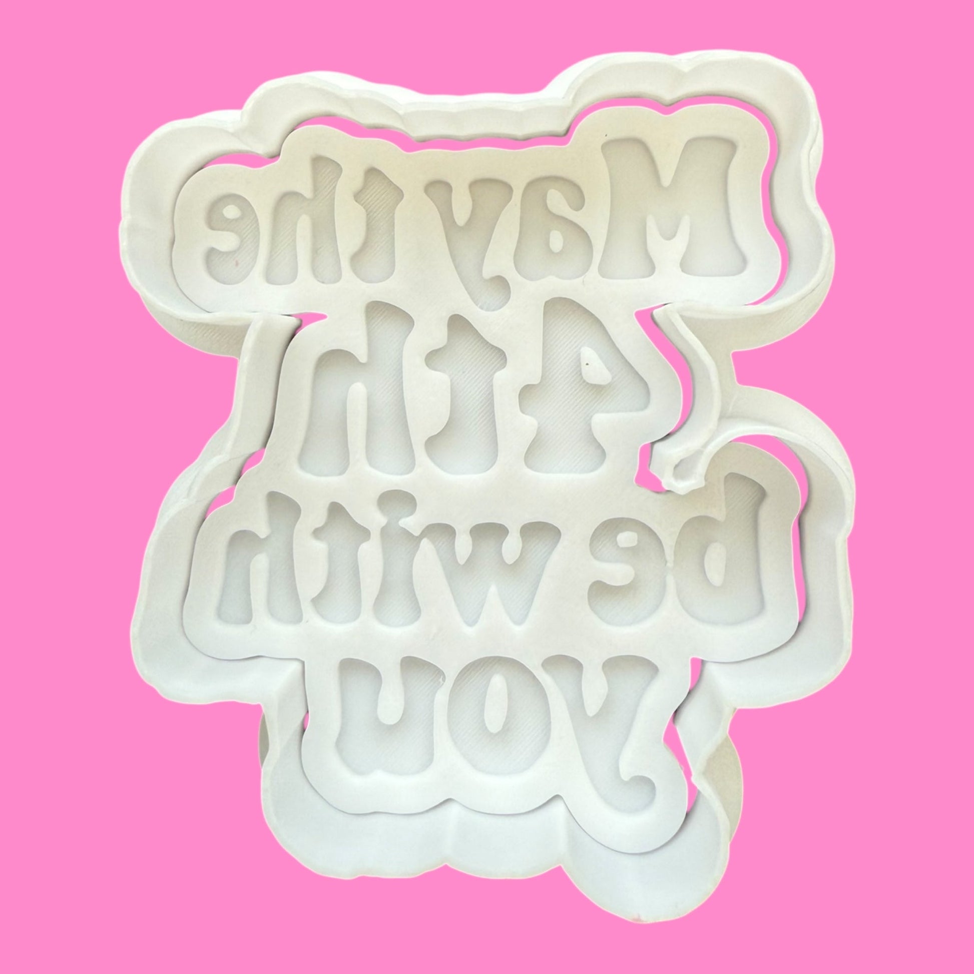 White cookie cutter with text on a pink background