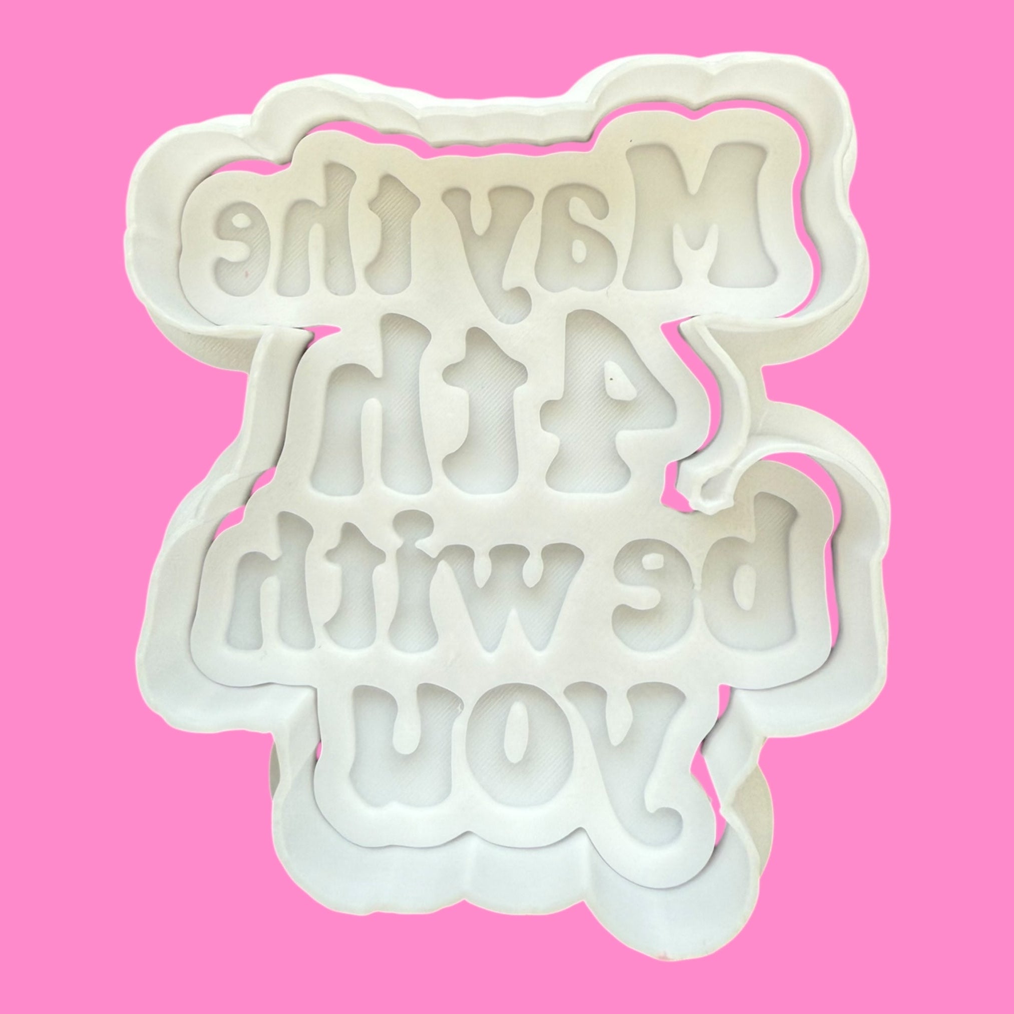 White cookie cutter with text on a pink background