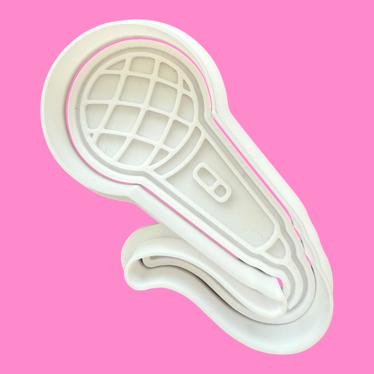 White plastic mold shaped like a shoe sole on a pink background