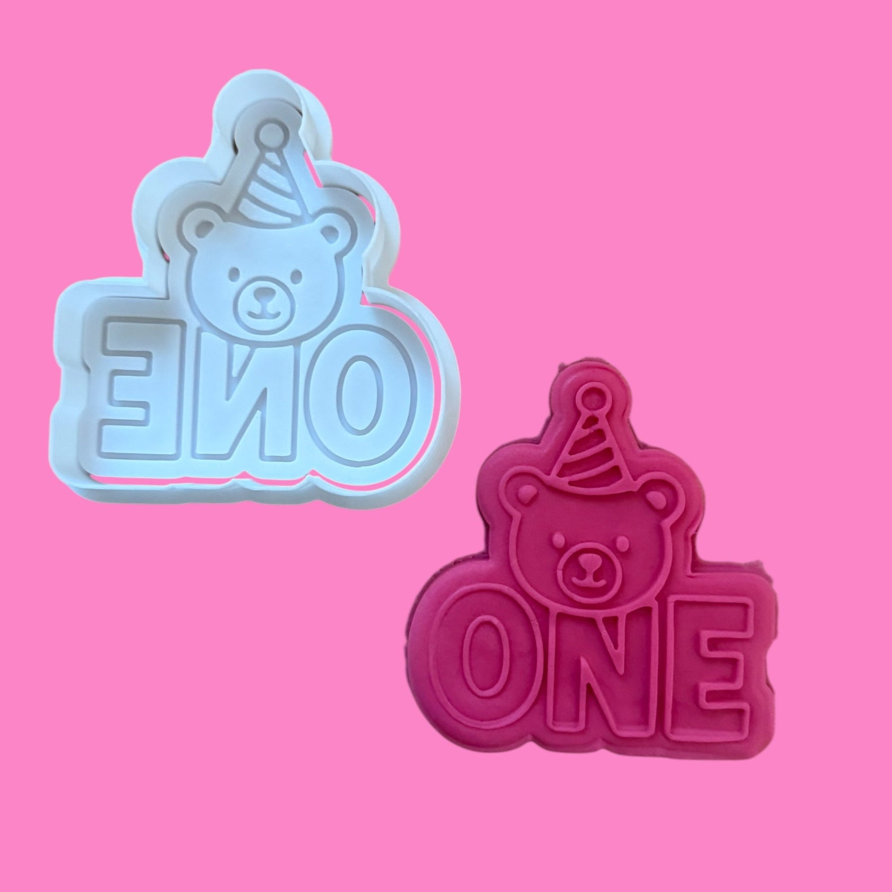 Two bear-shaped cookie cutters with 'ONE' text on a pink background