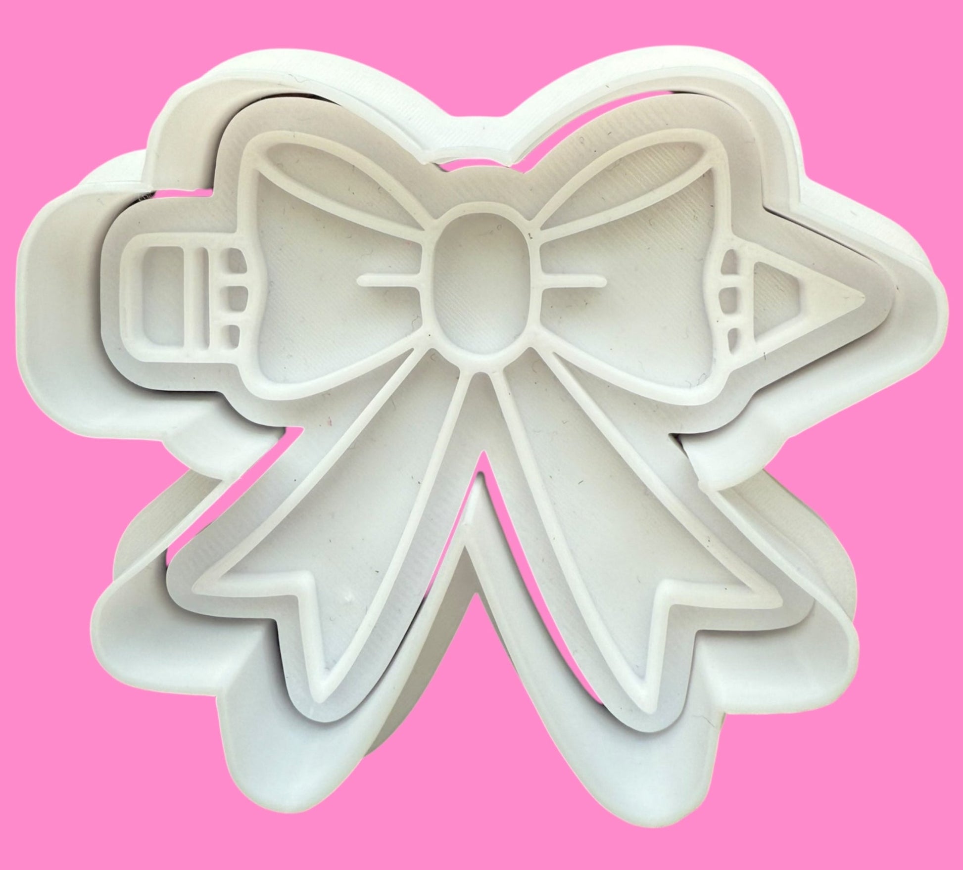 Bow-shaped cookie cutter on a pink background