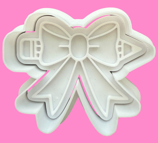 Bow-shaped cookie cutter on a pink background