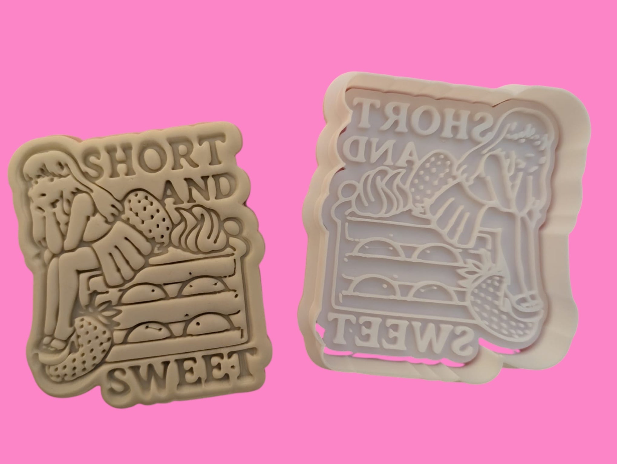 Two cookie cutters with embossed designs, one with the phrase 'Short and Sweet' and the other resembling a stacked outfit, both in pink color.