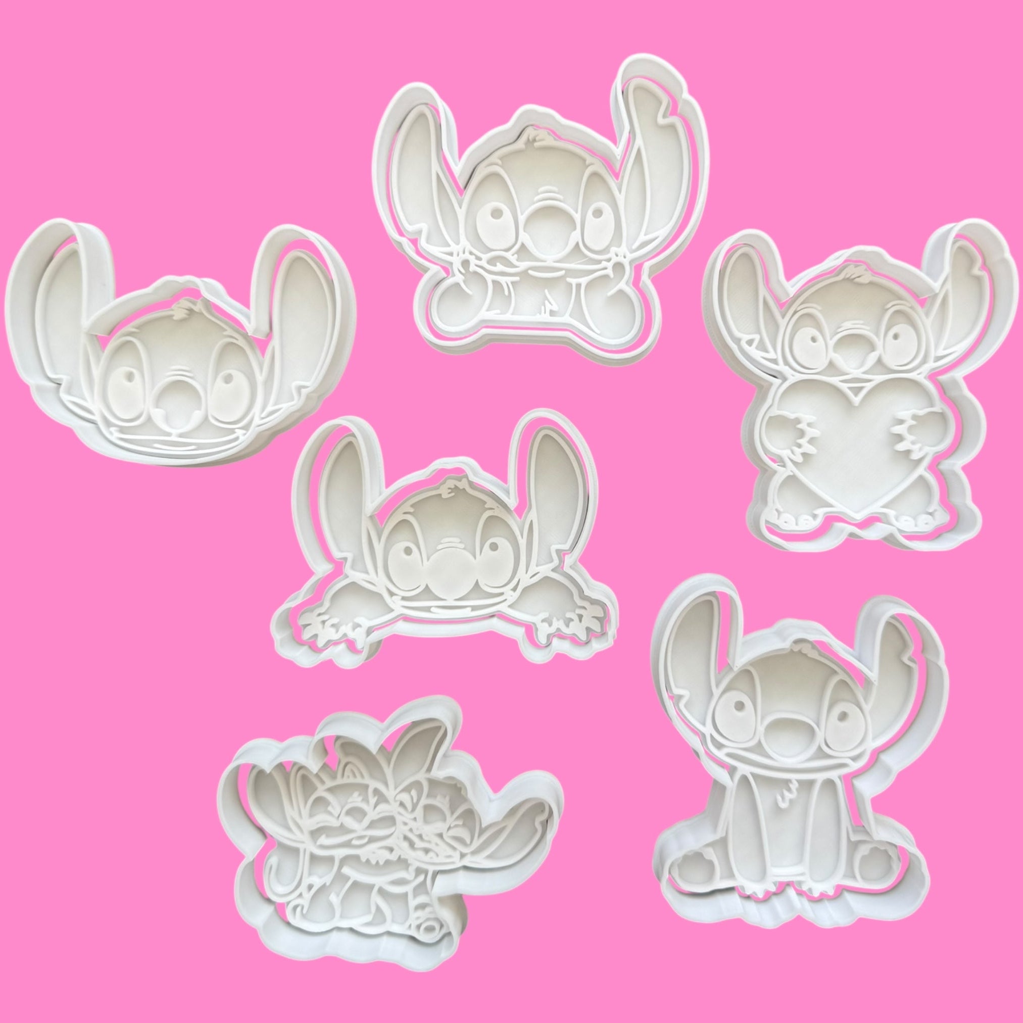Set of six white cartoon character cookie cutters on a pink background
