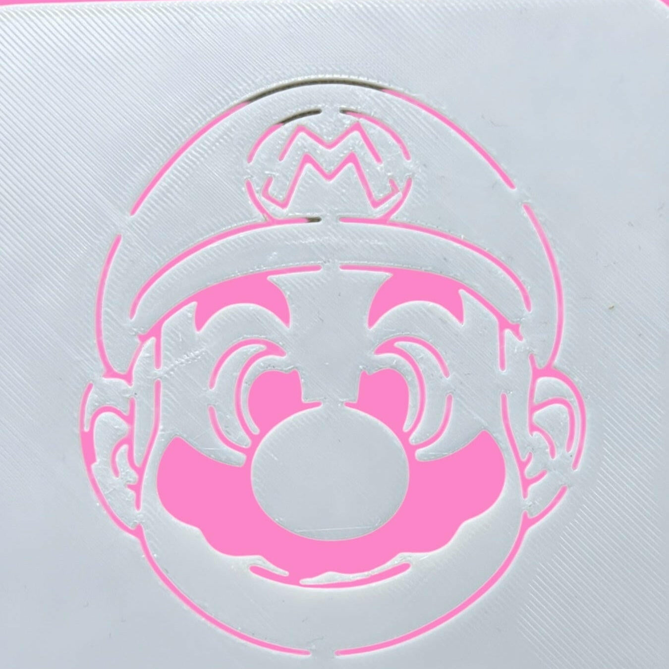 A white stencil with a Super Mario character design, designed for decorating cookies, cakes, and fondant.