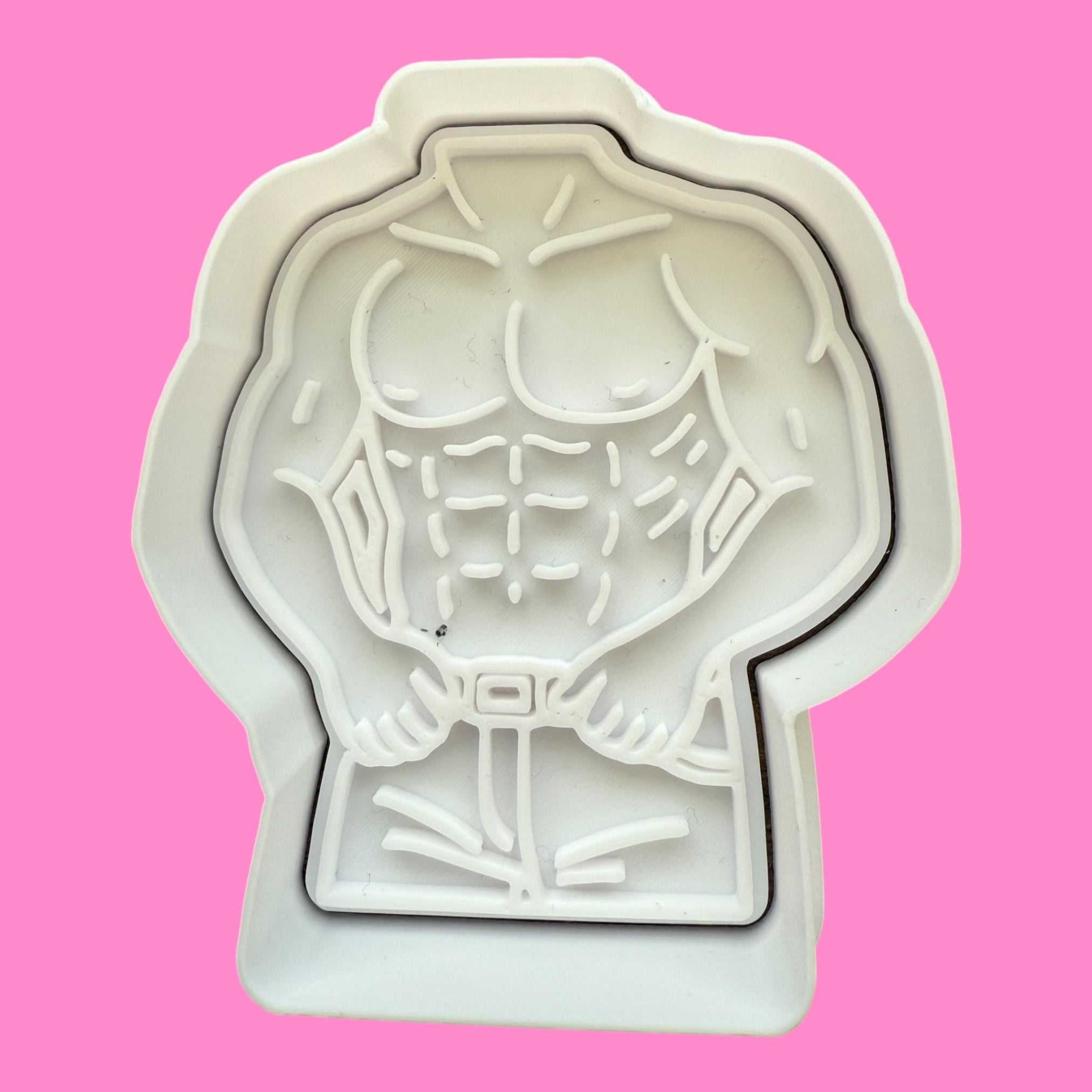 Cookie cutter shaped like a muscular figure on a pink background